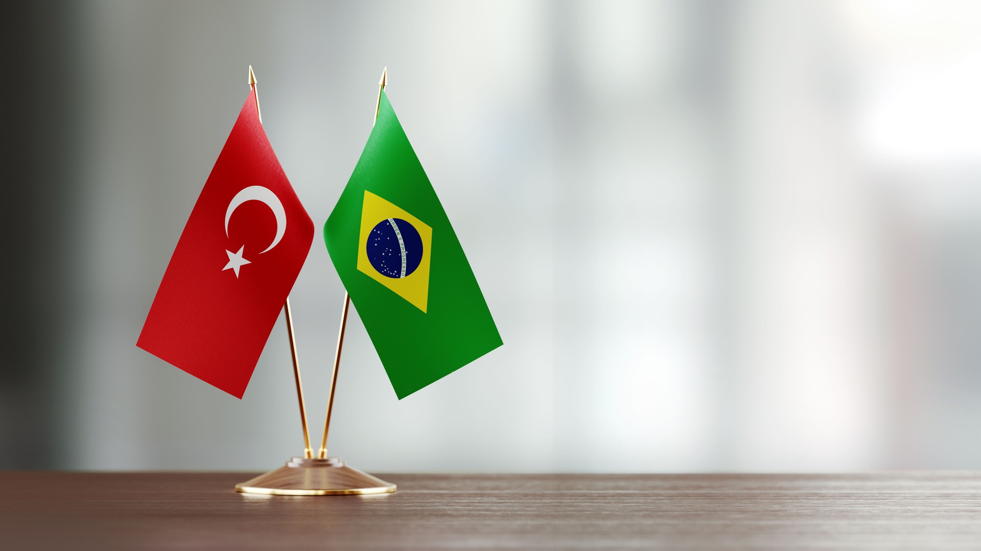 Turkish And Brazilian Flag Pair On A Desk Over Defocused Background